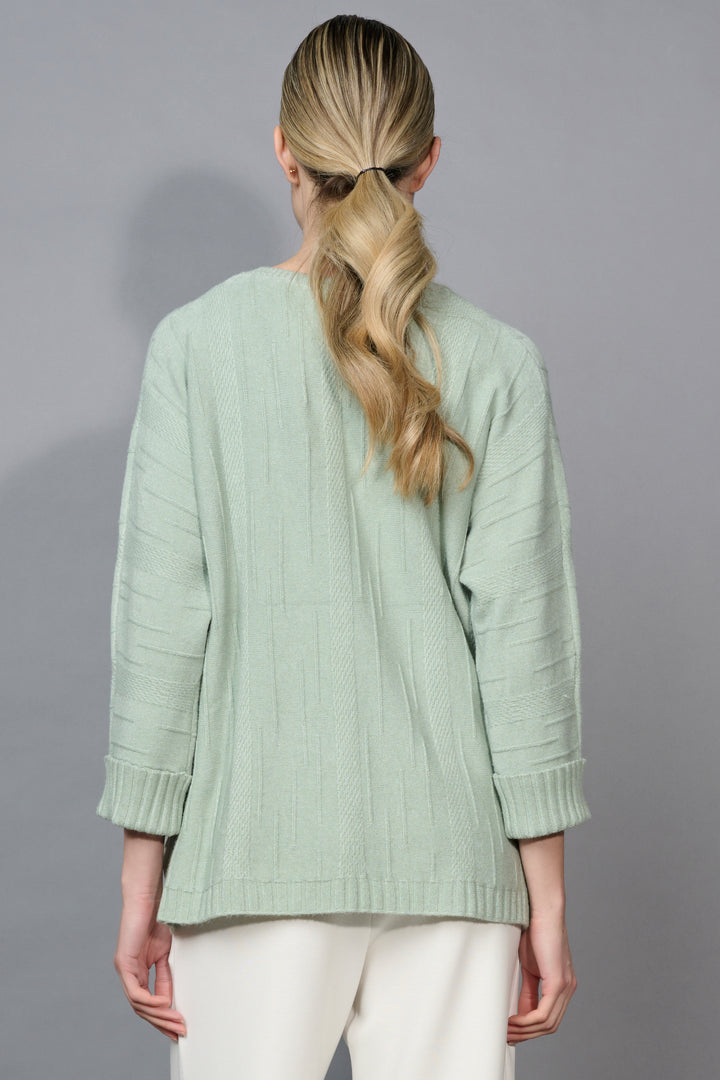 Person wearing a light green sweater with a plain background