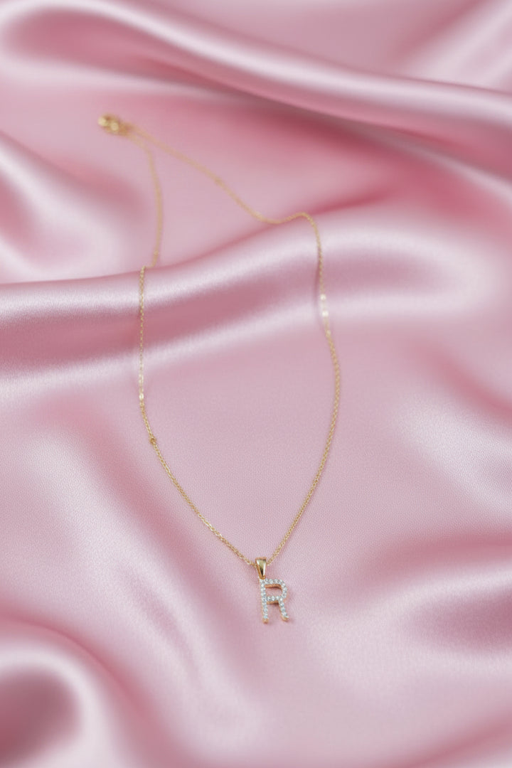 A delicate gold chain necklace with a small letter &