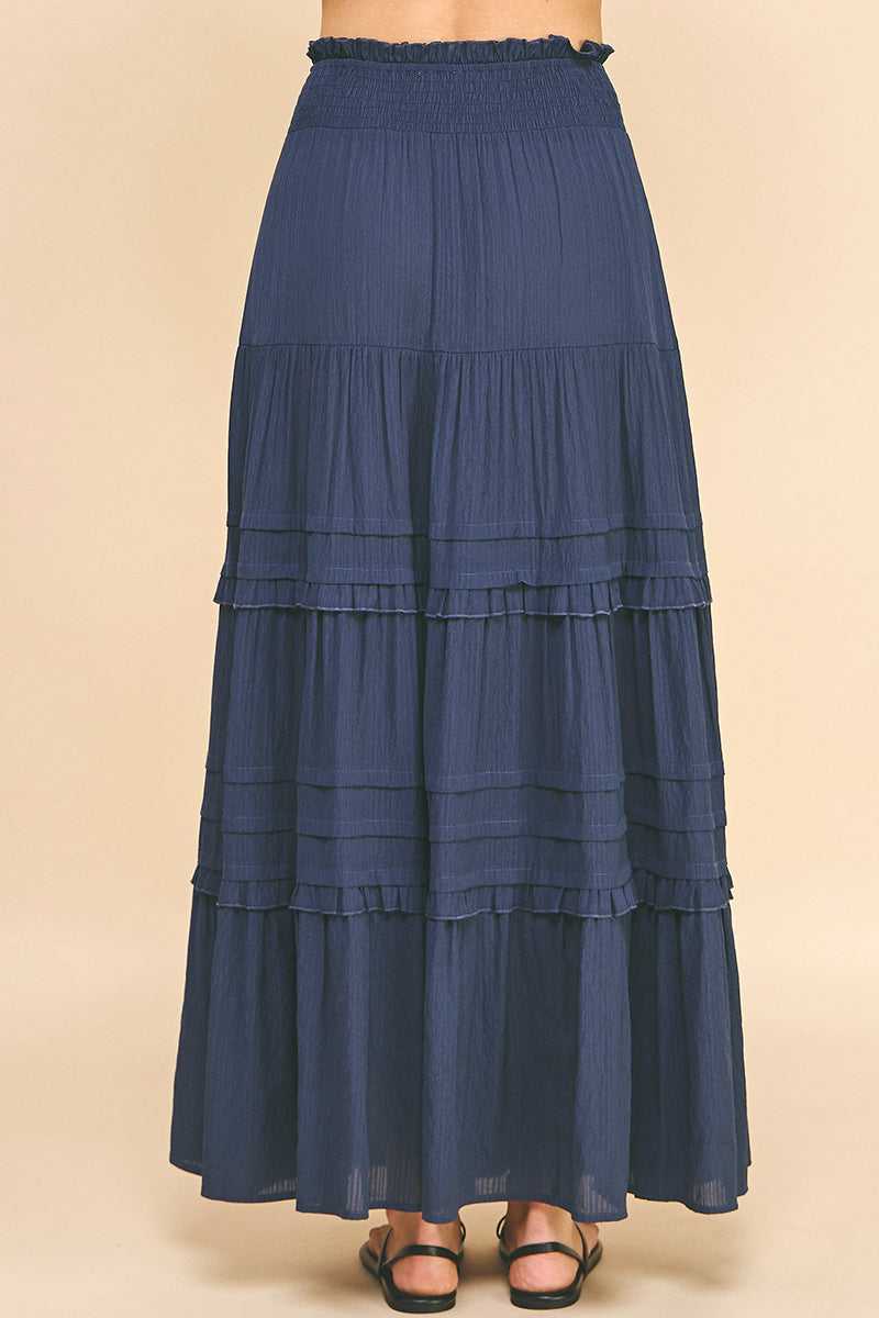 The Tiered Maxi Skirt in Dusty Navy color. A back view.