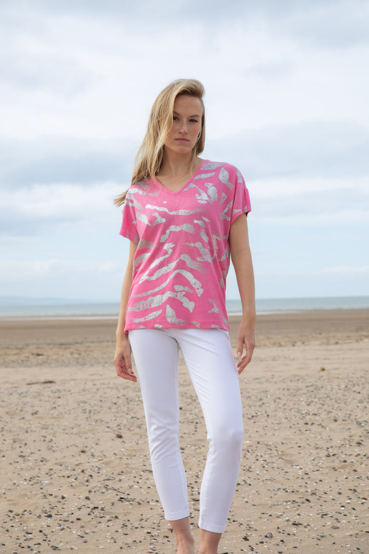The model is showing the Marble V-Neck Foil Print Top in Pink with white pants.