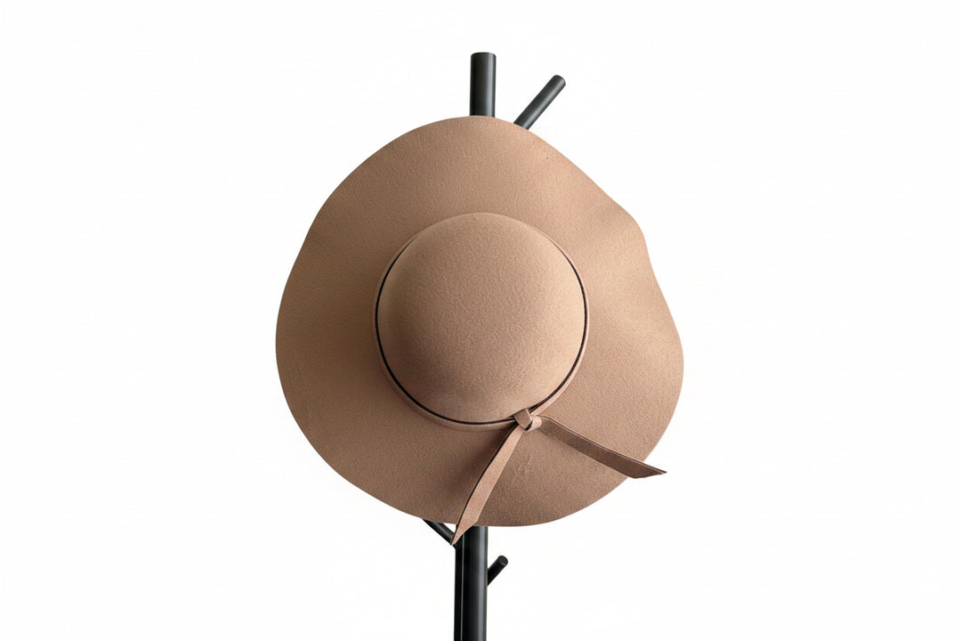 A wide-brimmed felt hat in a Camel color, displayed on a black coat rack.