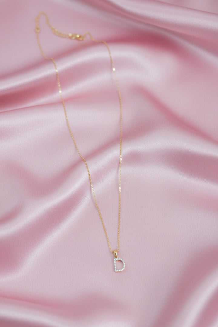 A delicate gold chain necklace with a small capital letter &