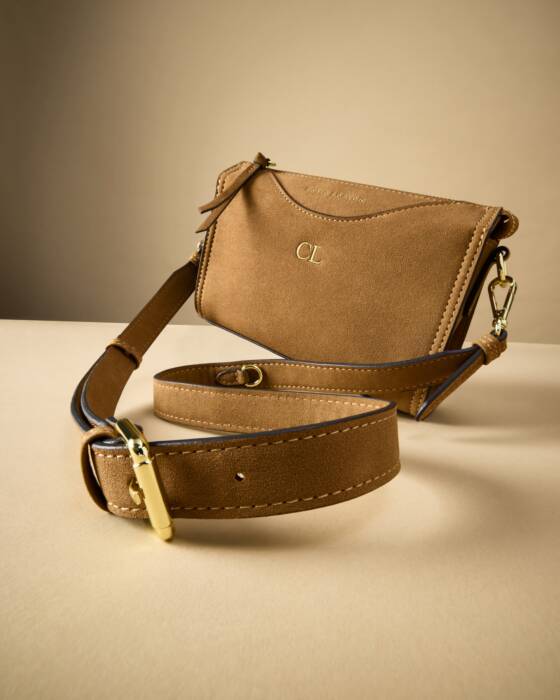 Brown leather bag with matching strap on a beige background