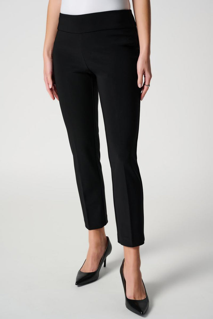 Person wearing black pants and black shoes on a white background