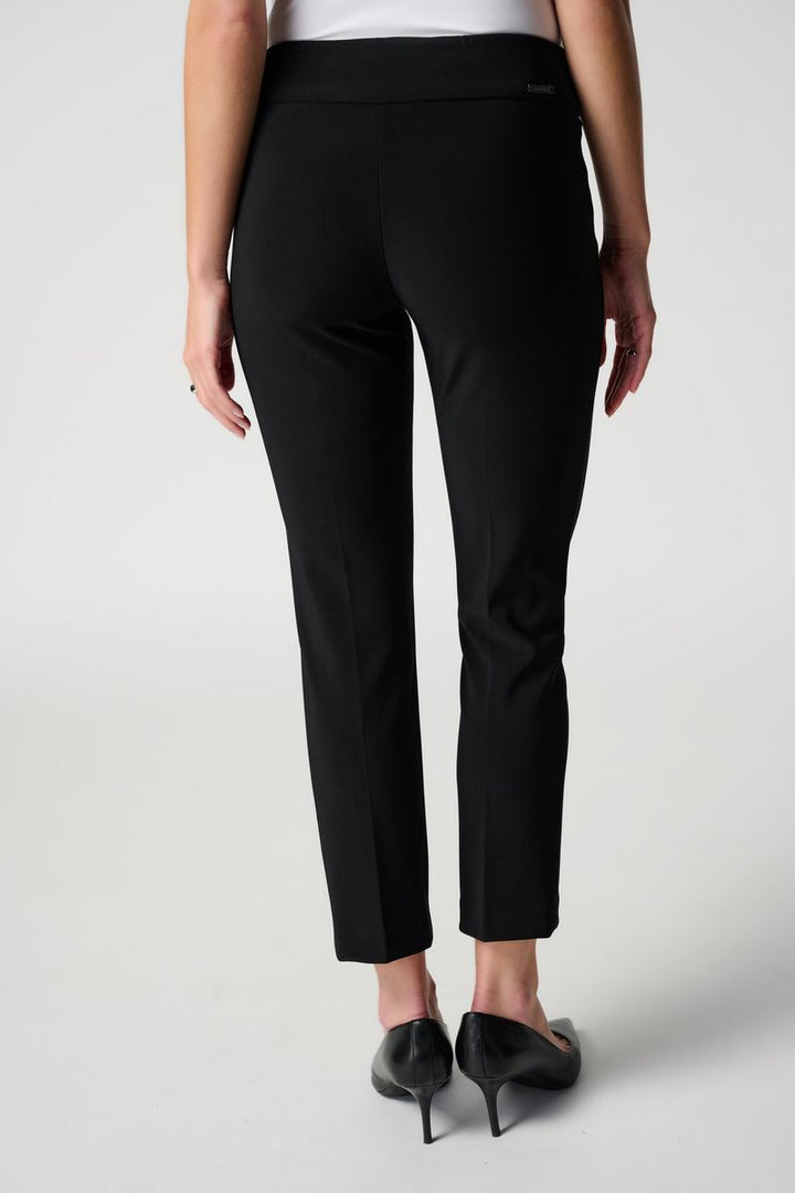 Black pants worn by a person on a white background, a back view