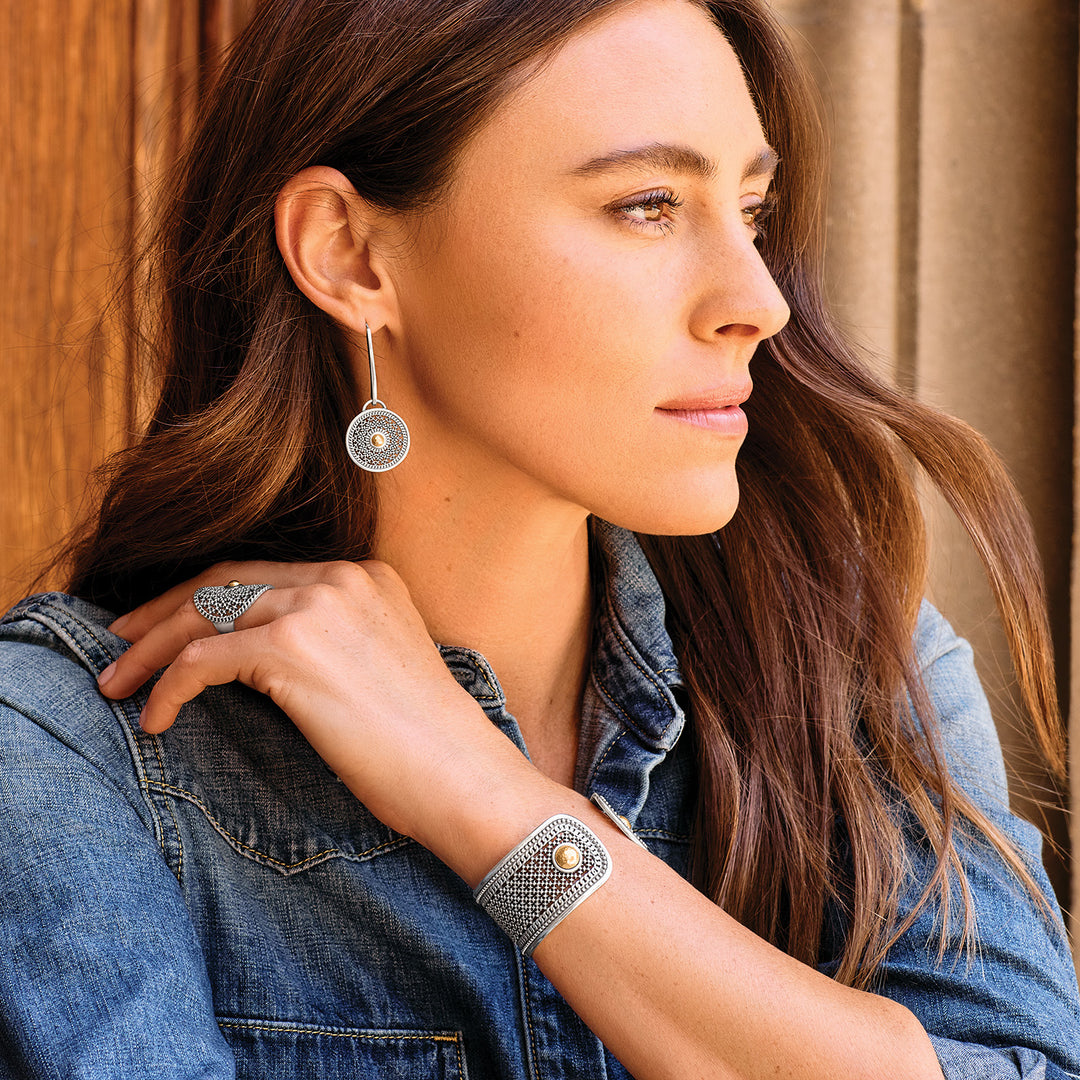 Woman wearing silver earrings and bracelet against a wooden background