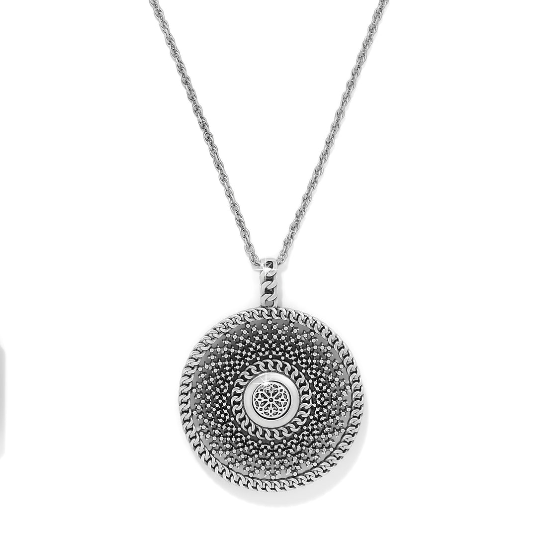 Silver necklace with a round, intricate pendant on a white background, the back of the pendant