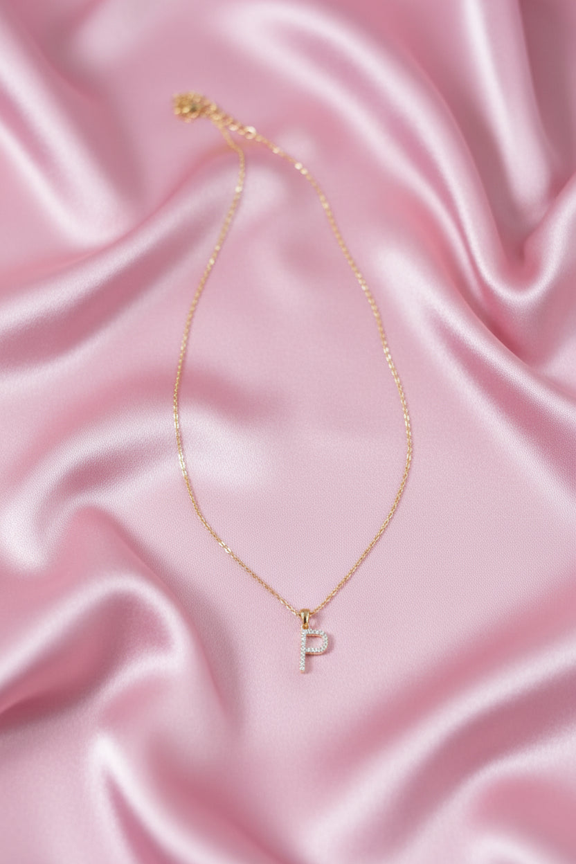 A delicate gold chain necklace with a small cubic zirconia stones pave letter &