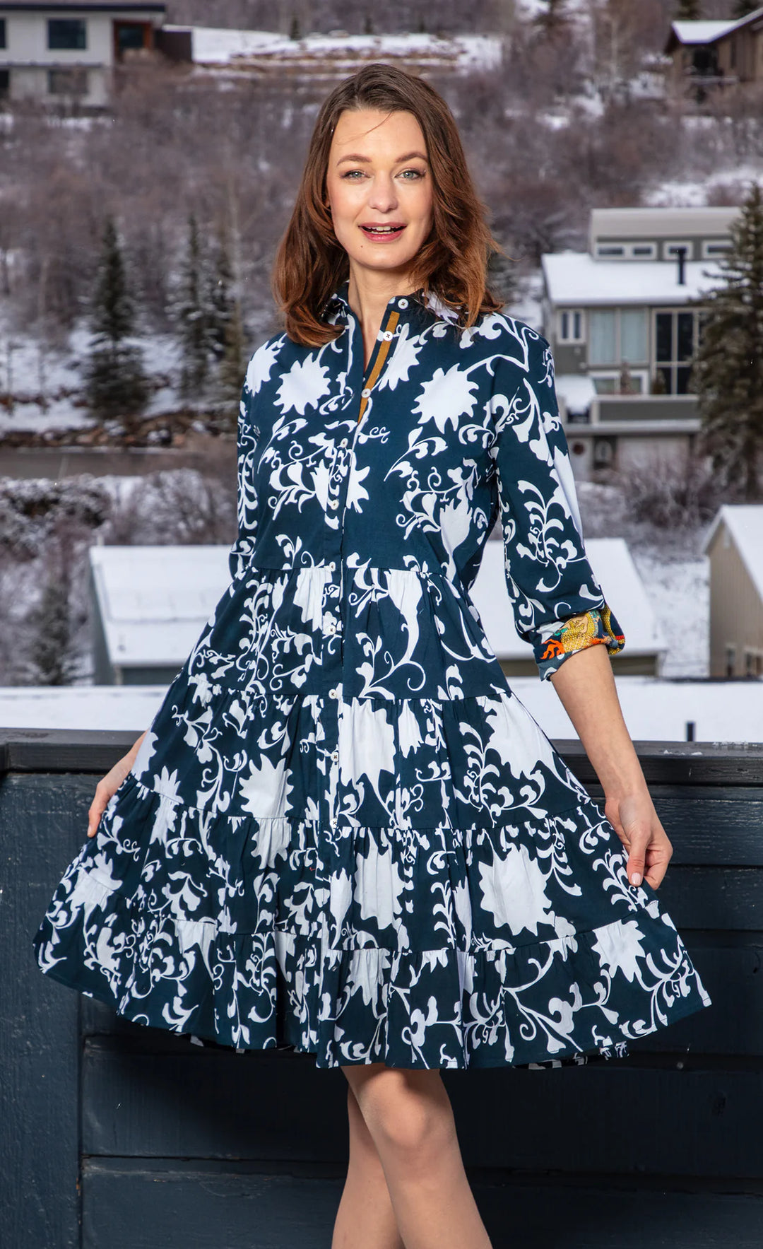 A woman wearing a floral navy and white dress in midi length with a wintery background.