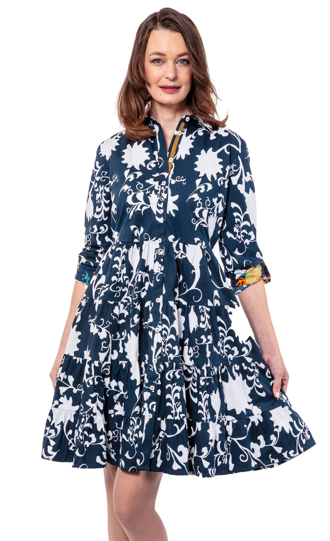 A woman wearing a floral navy and white dress in midi length with a white background.
