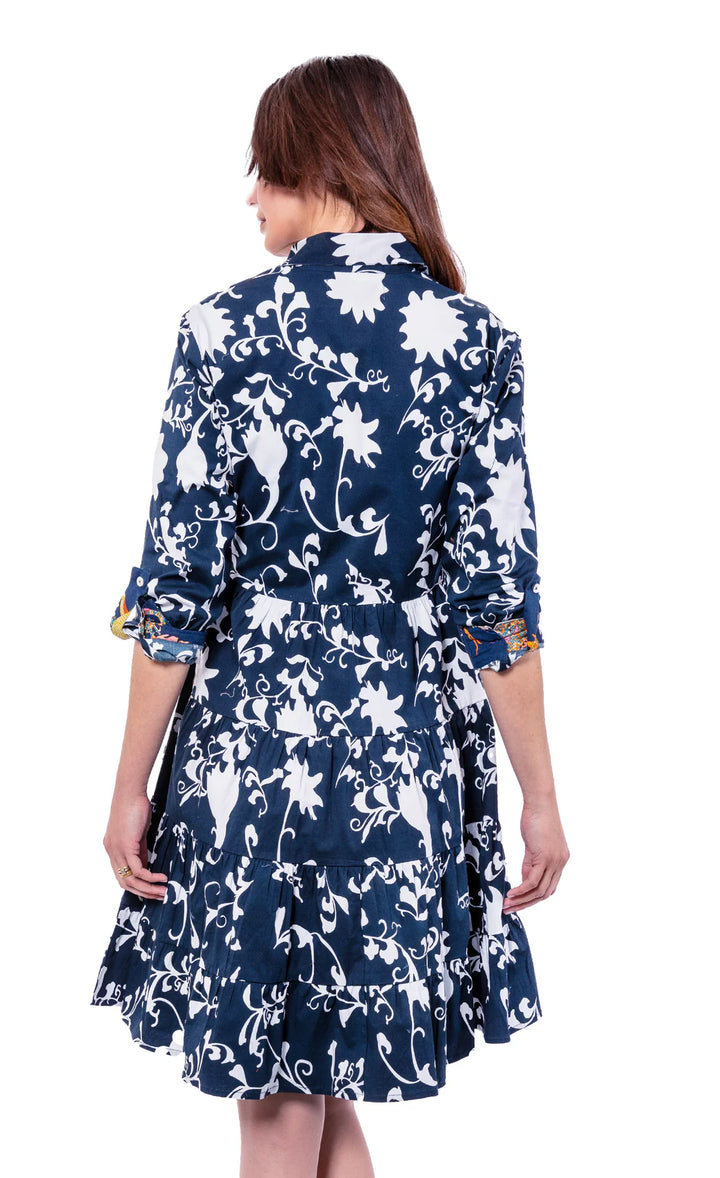 A back view of a woman wearing a floral navy and white dress with a white background.