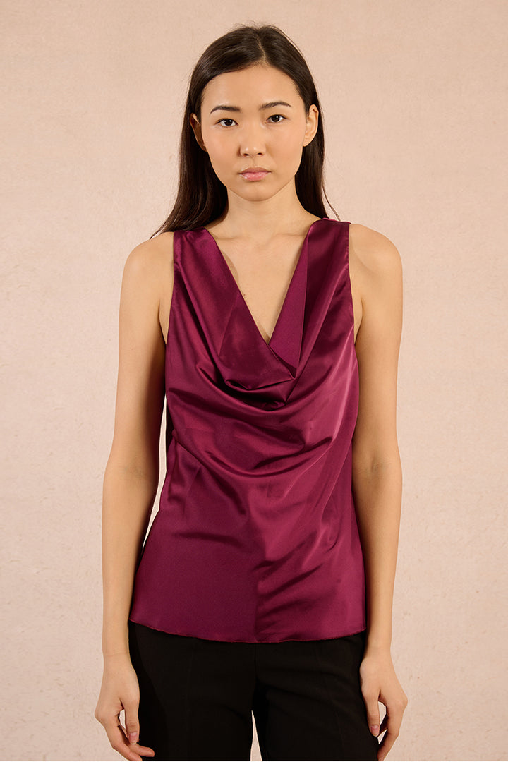 Woman wearing a dark pink satin top against a beige background