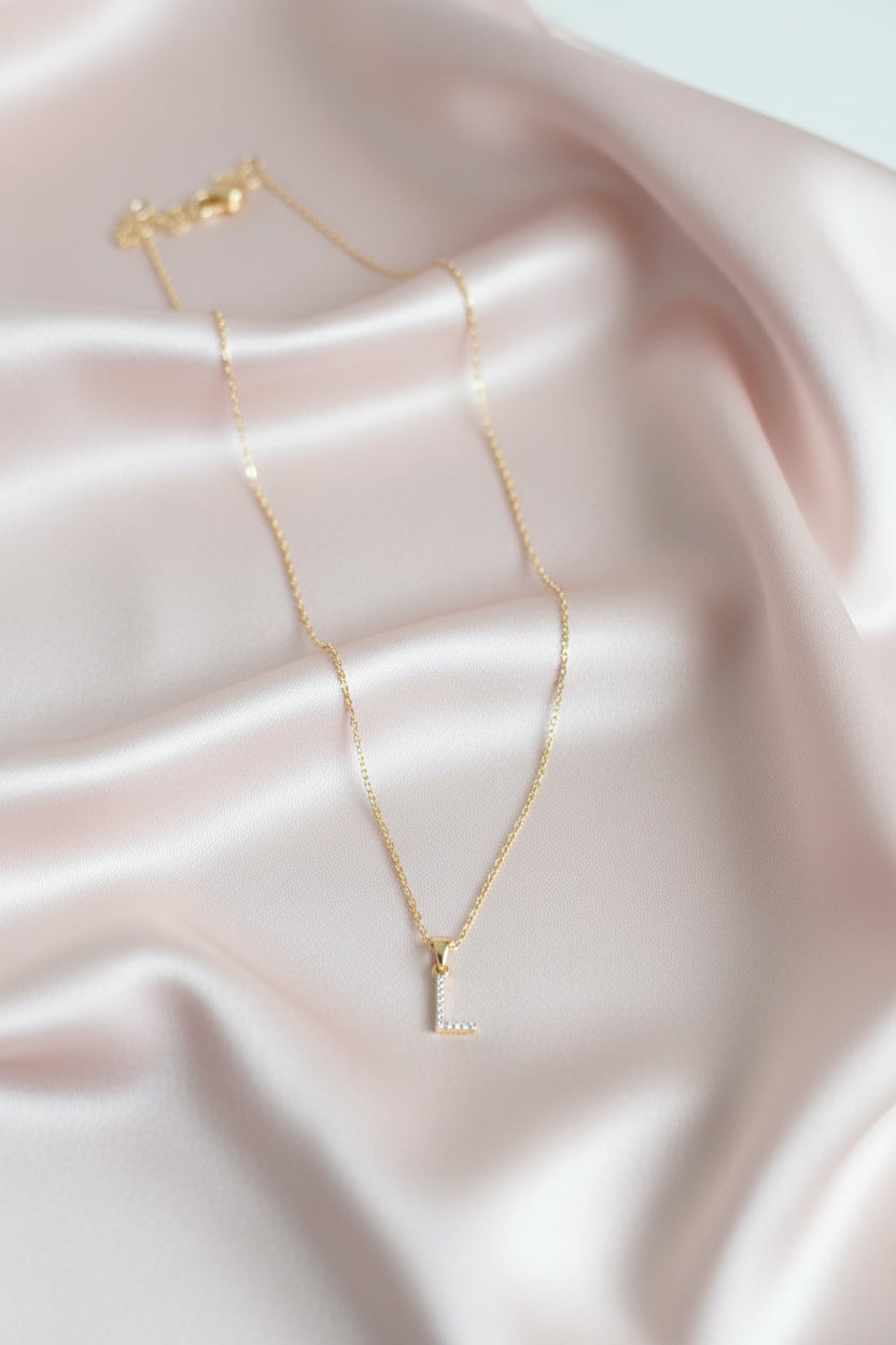 A delicate gold chain necklace with a small cubic zirconia stones pave letter &