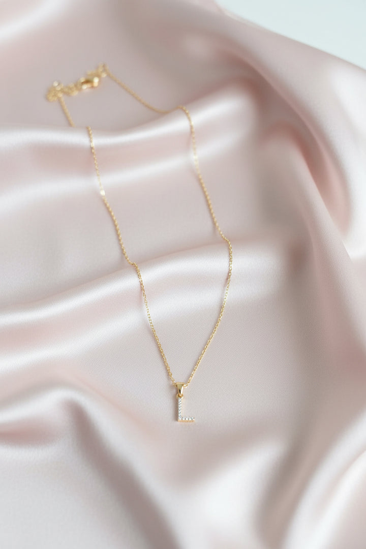 A delicate gold chain necklace with a small cubic zirconia stones pave letter &