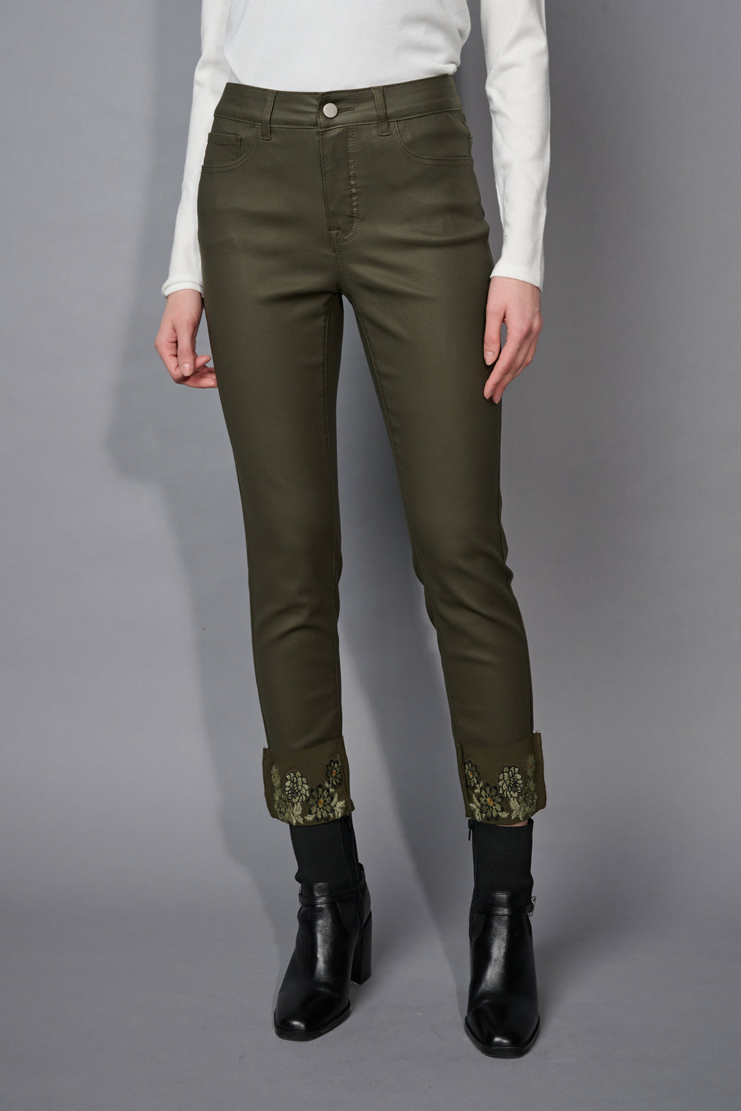 Person wearing olive green pants with sequin cuffs on a gray background