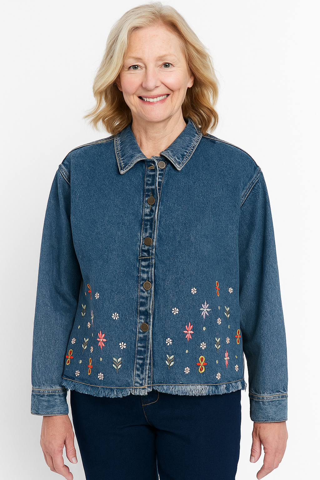 Woman wearing a blue denim jacket with floral embroidery on a white background