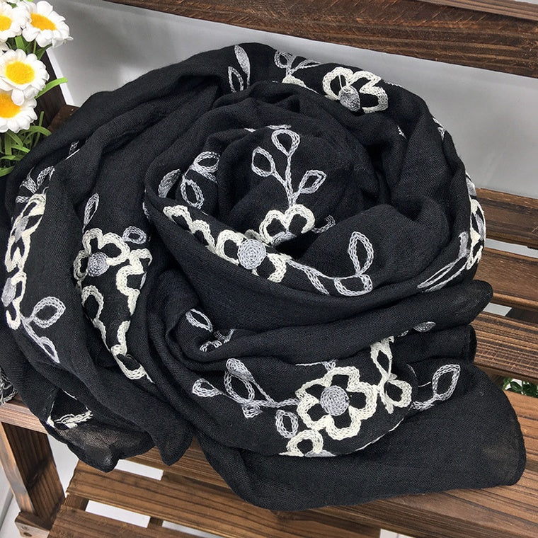 Black scarf with white floral patterns on a wooden surface
