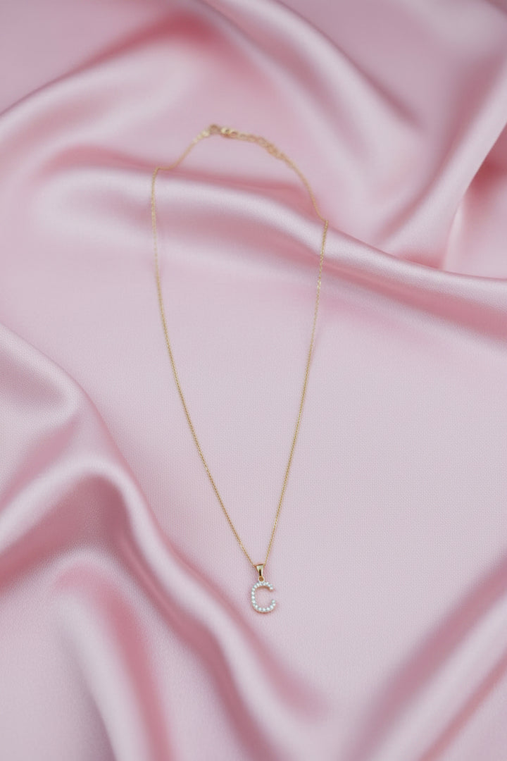A delicate gold chain necklace with a small letter &