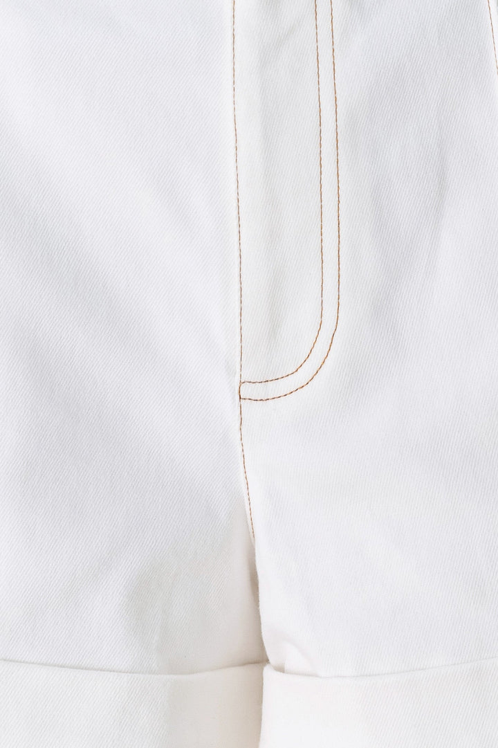 Close-up of a white garment with a gold thread seam on a white background