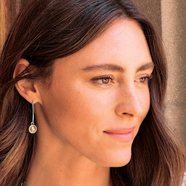Close-up of a woman wearing earrings with a neutral background