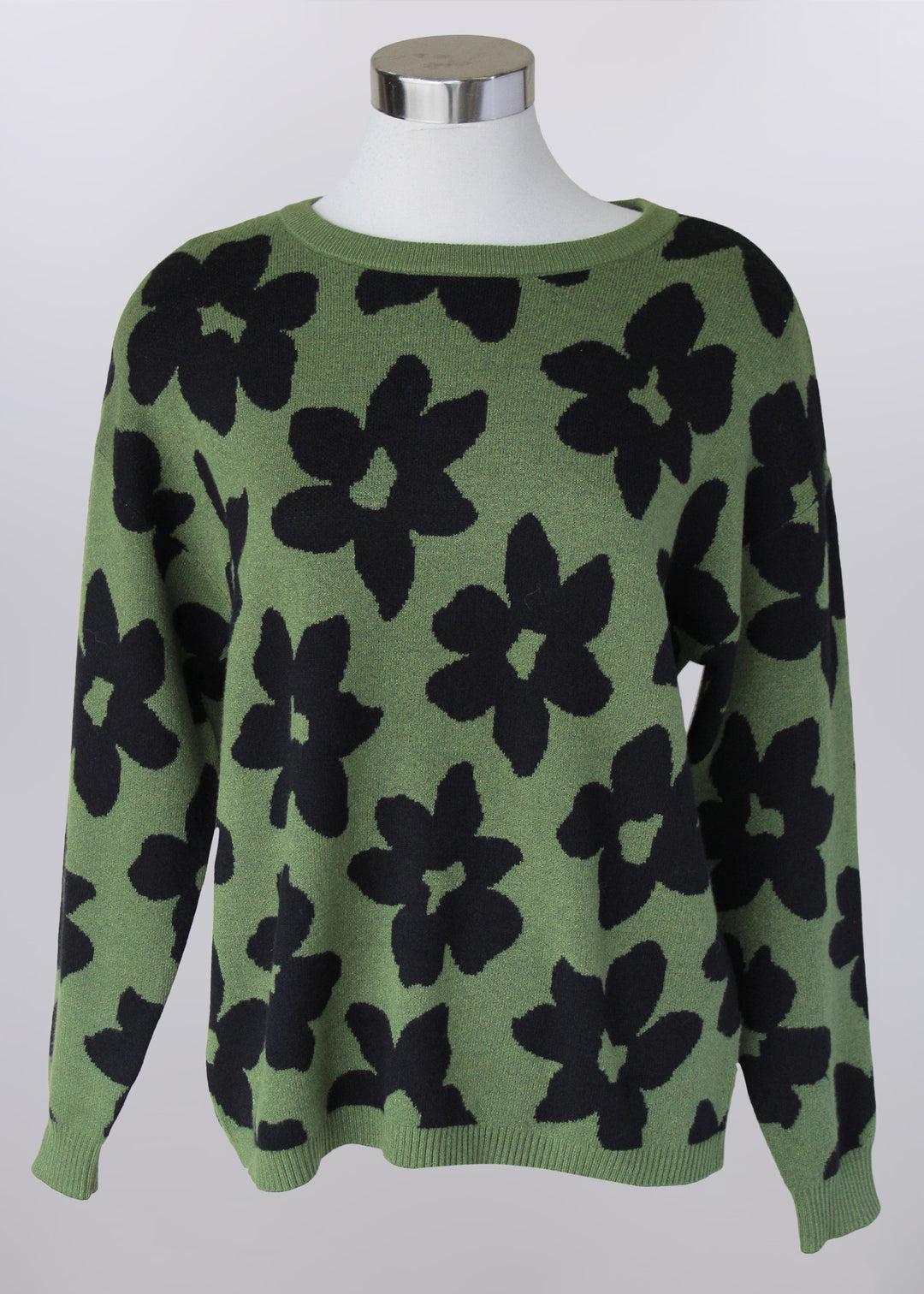 Green sweater with black floral pattern on a mannequin against a white background