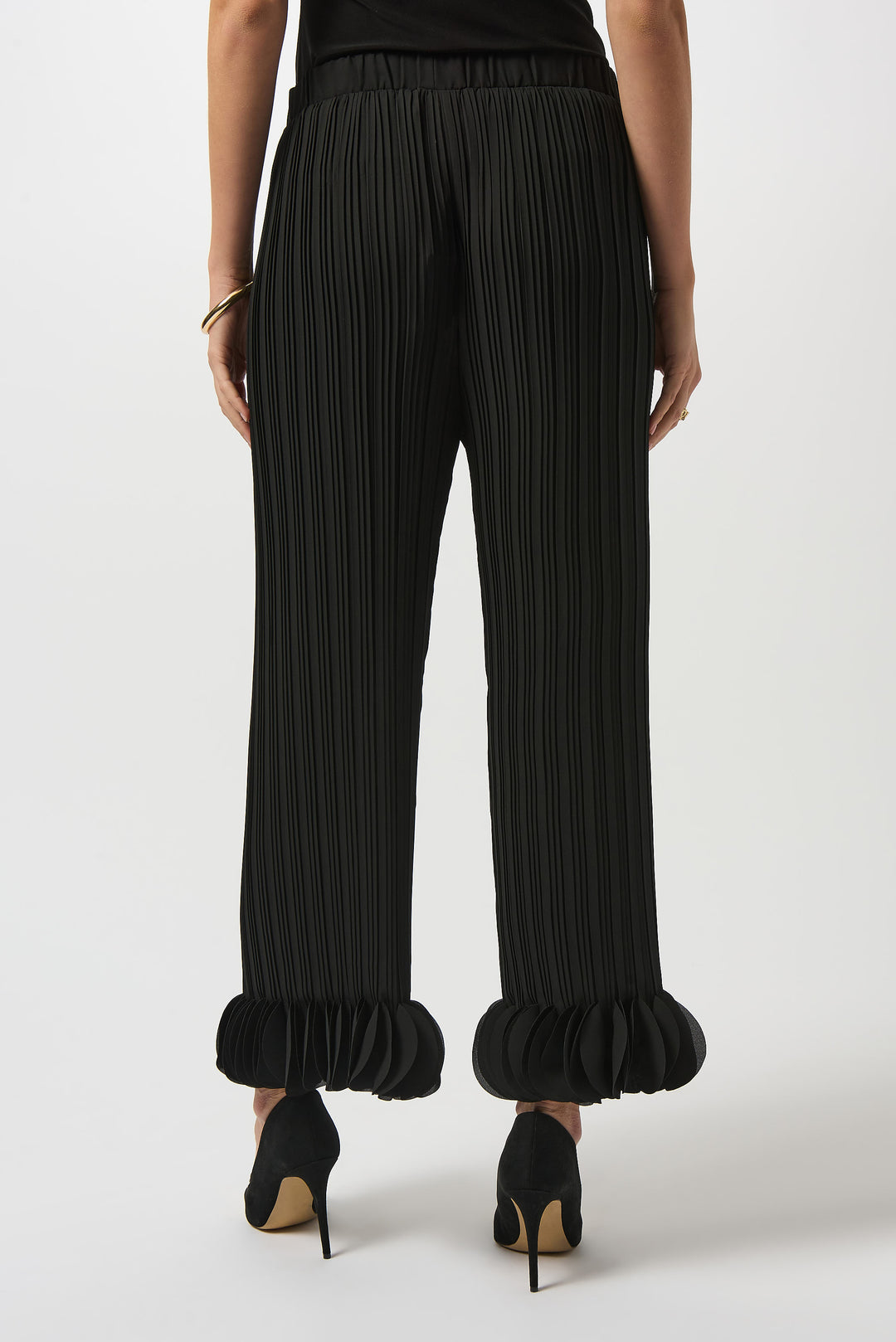 a back view of a black ruffled pants worn by a person on a white background