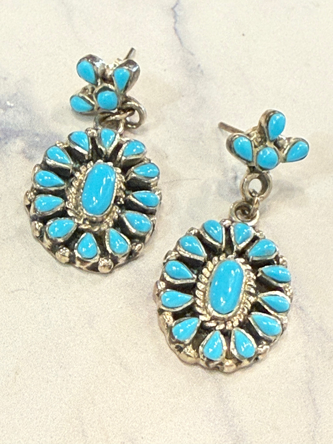 Pair of turquoise stone earrings on a textured white background
