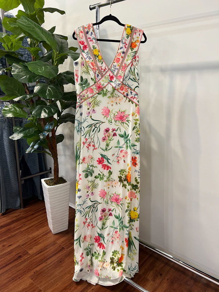 Floral dress hanging on a rack with a plant and white wall in the background