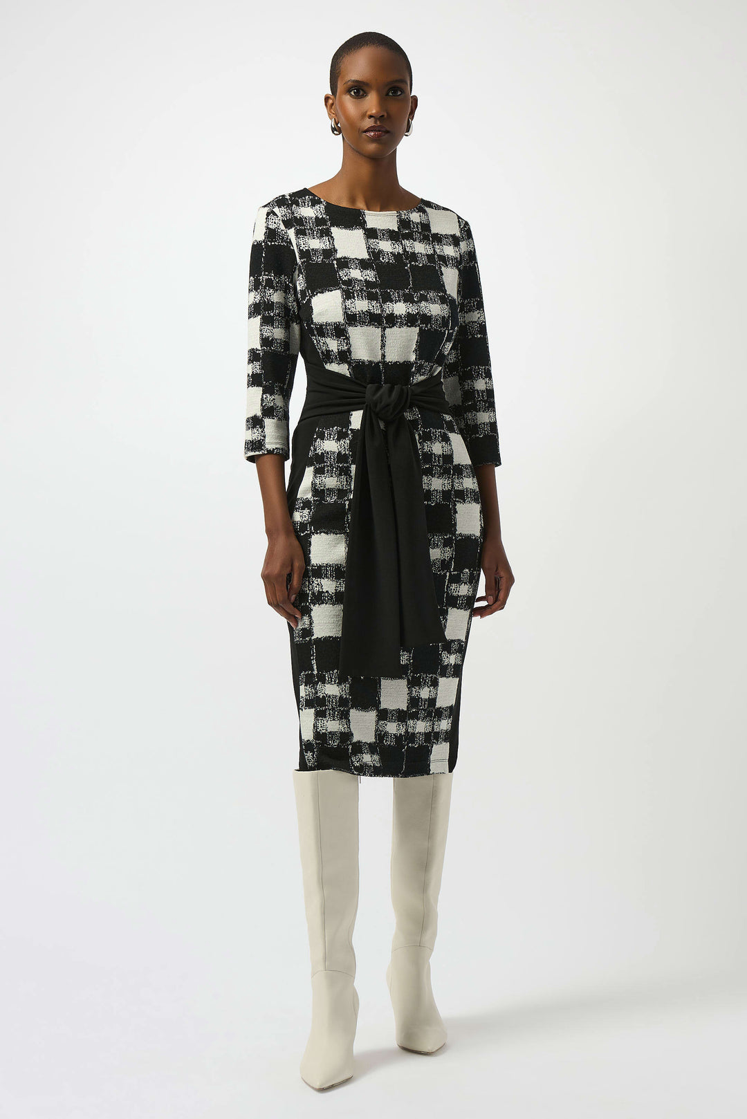 Woman wearing a black and white checkered dress with a belt on a white background