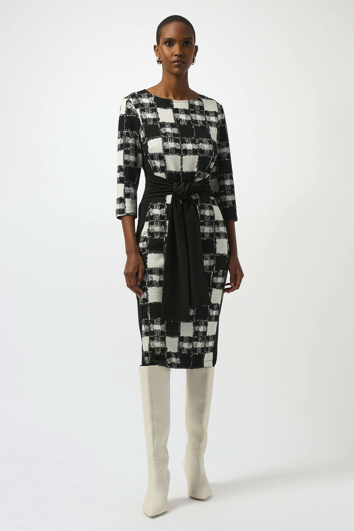 Woman wearing a black and white checkered dress with a belt on a white background