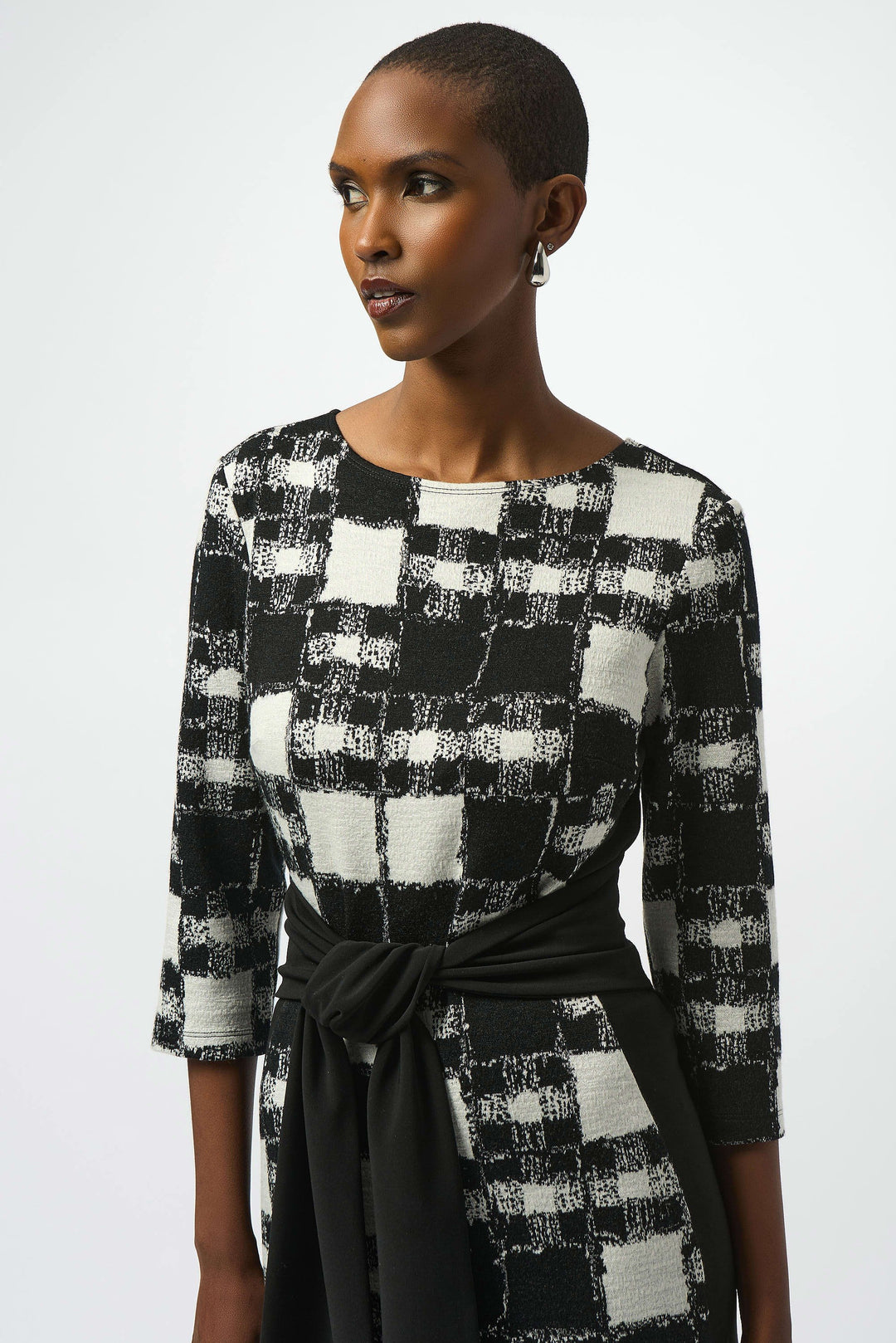 Woman wearing a black and white checkered dress with a plain background