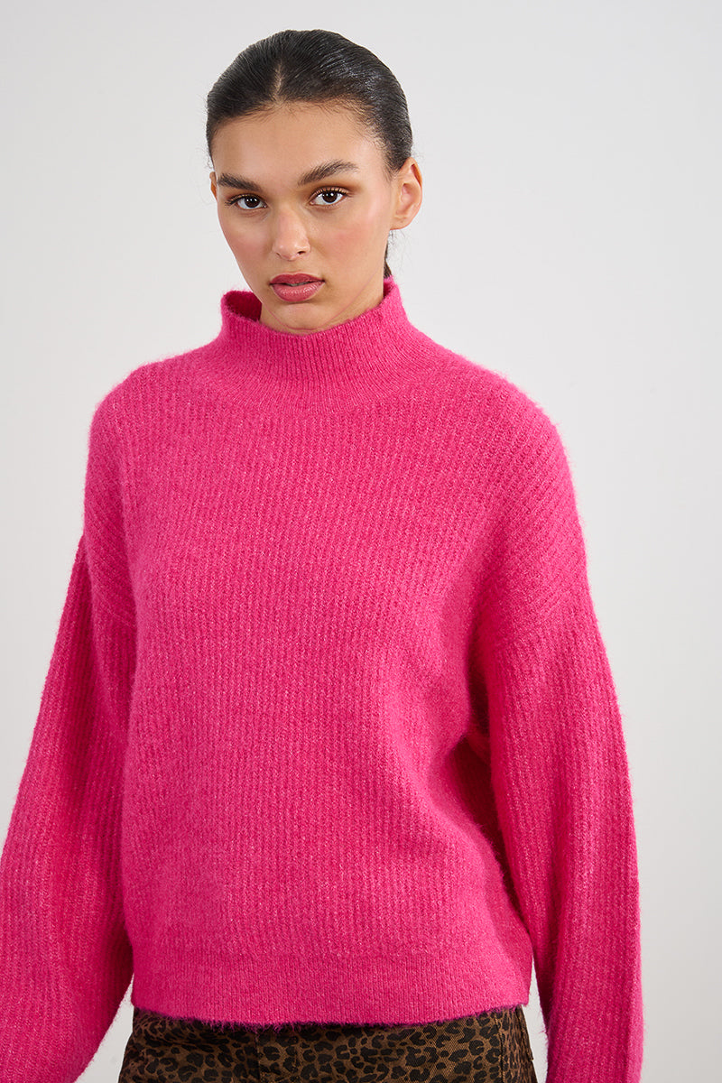 Woman wearing a bright pink sweater against a plain background