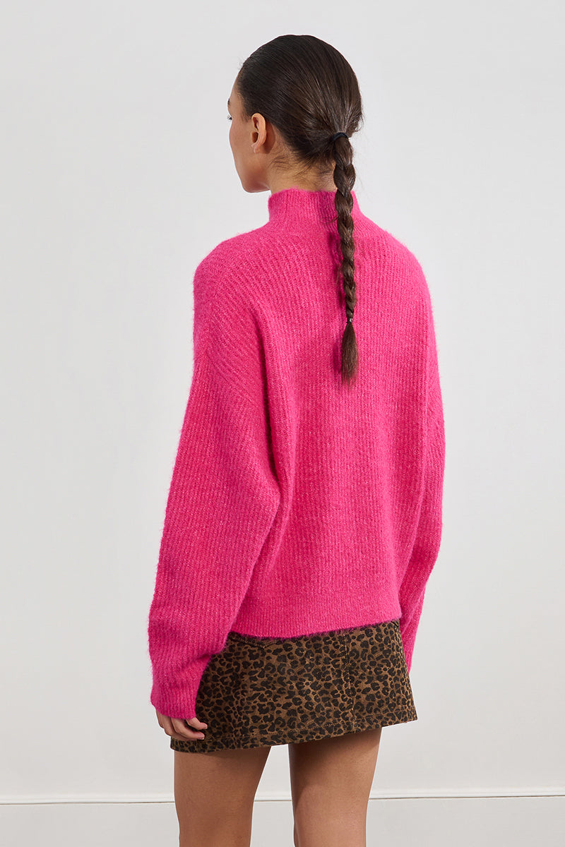 A back view of a person wearing a bright pink sweater and leopard print skirt on a white background