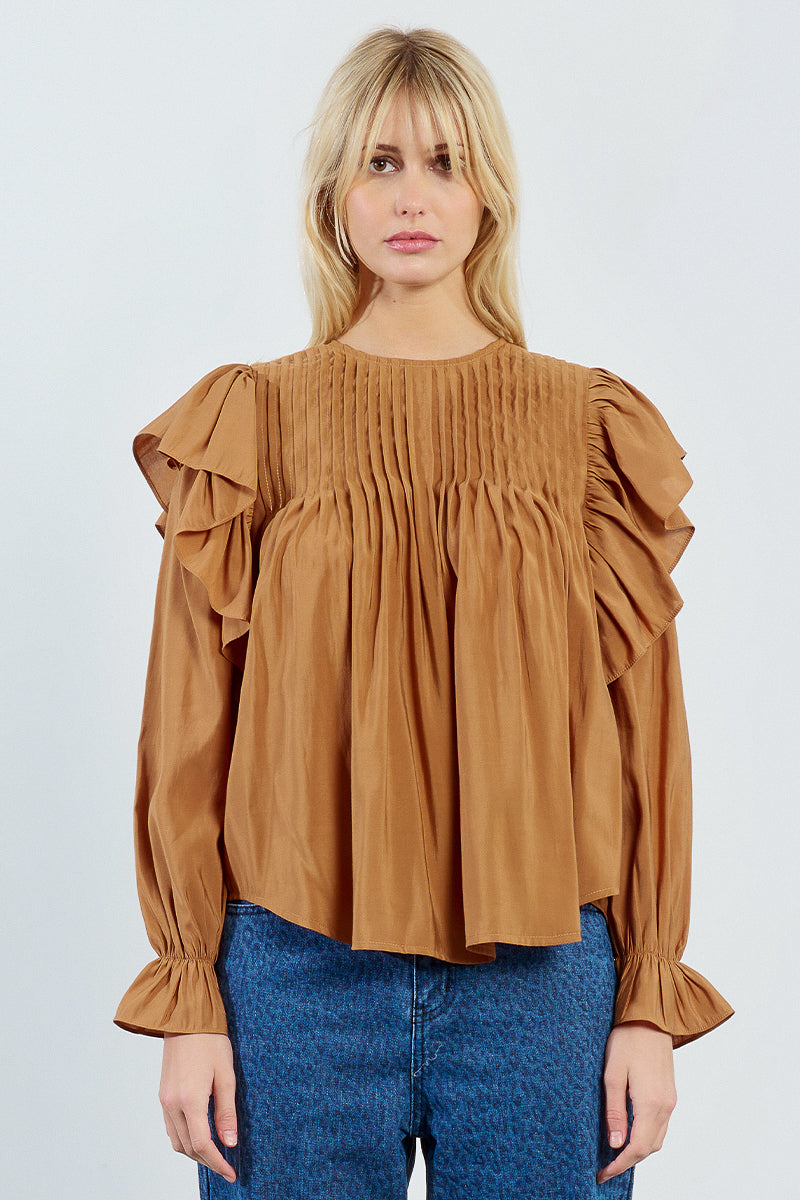 Woman wearing a brown blouse with ruffled sleeves on a white background