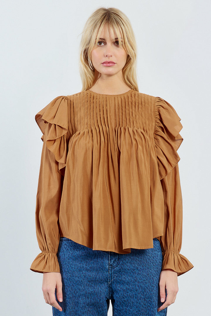 Woman wearing a brown blouse with ruffled sleeves on a white background