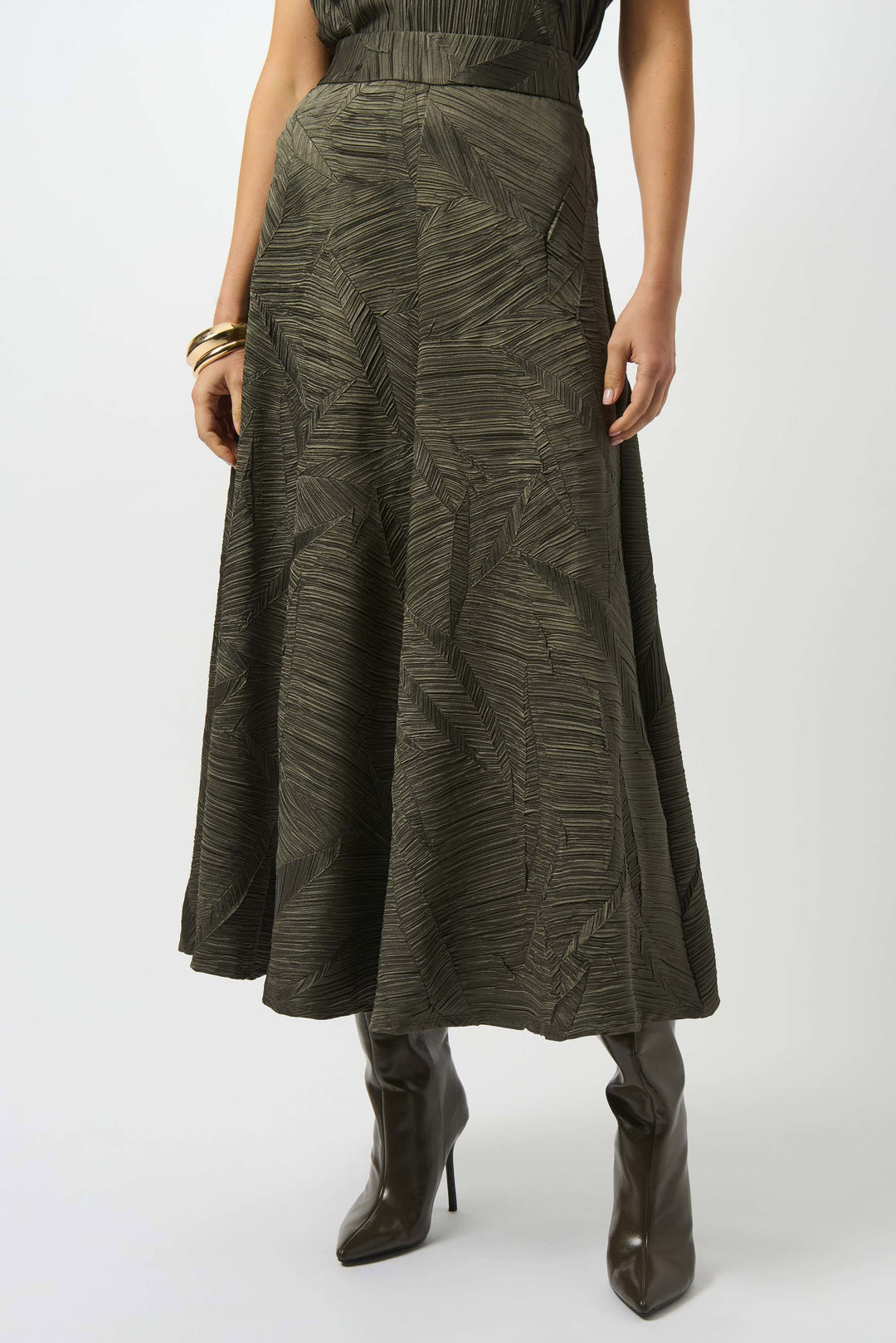 Person wearing a long green skirt with a subtle pattern on a white background