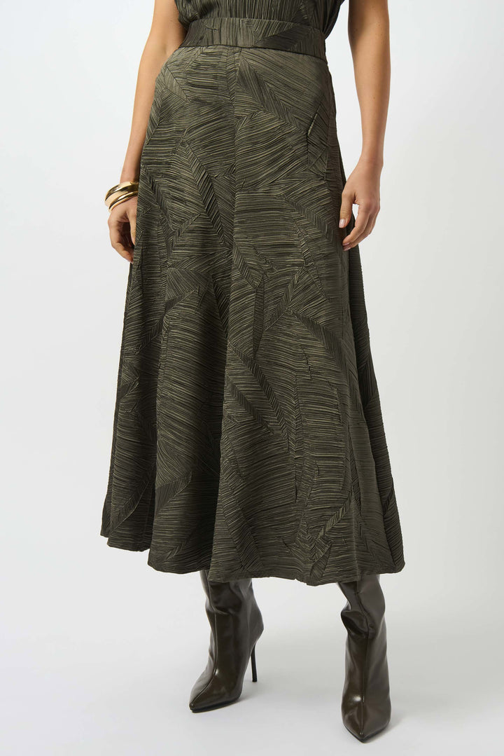 Person wearing a long green skirt with a subtle pattern on a white background