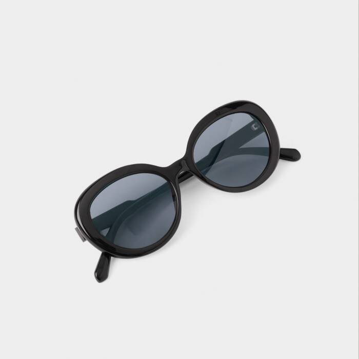 Black sunglasses with dark lenses on a light gray background