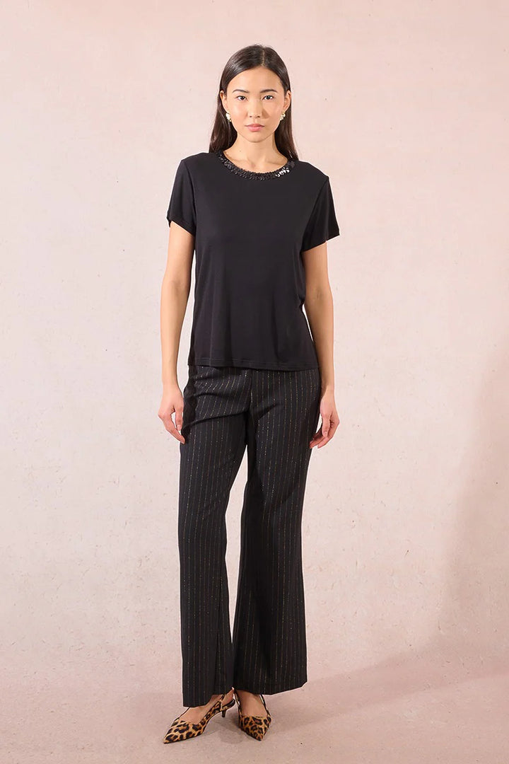 Woman wearing a black top and striped pants on a plain background