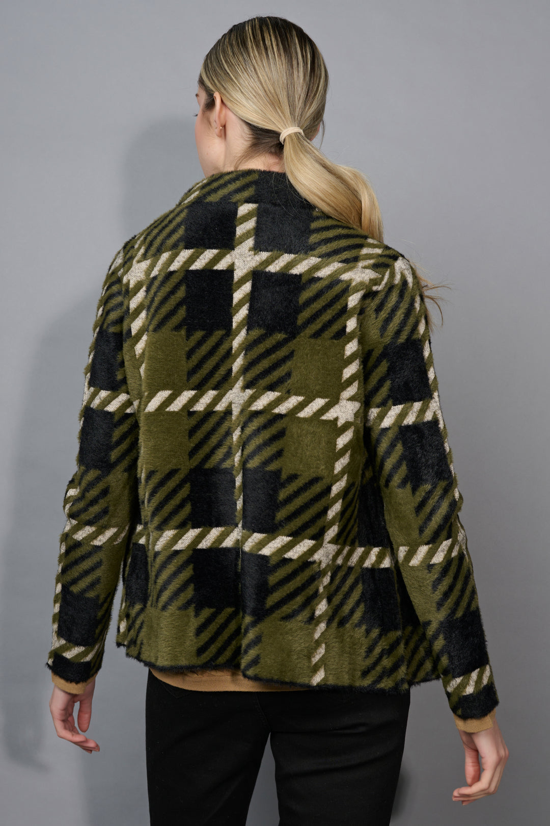 A back view of a person wearing a plaid jacket with green, black, and beige pattern on a gray background