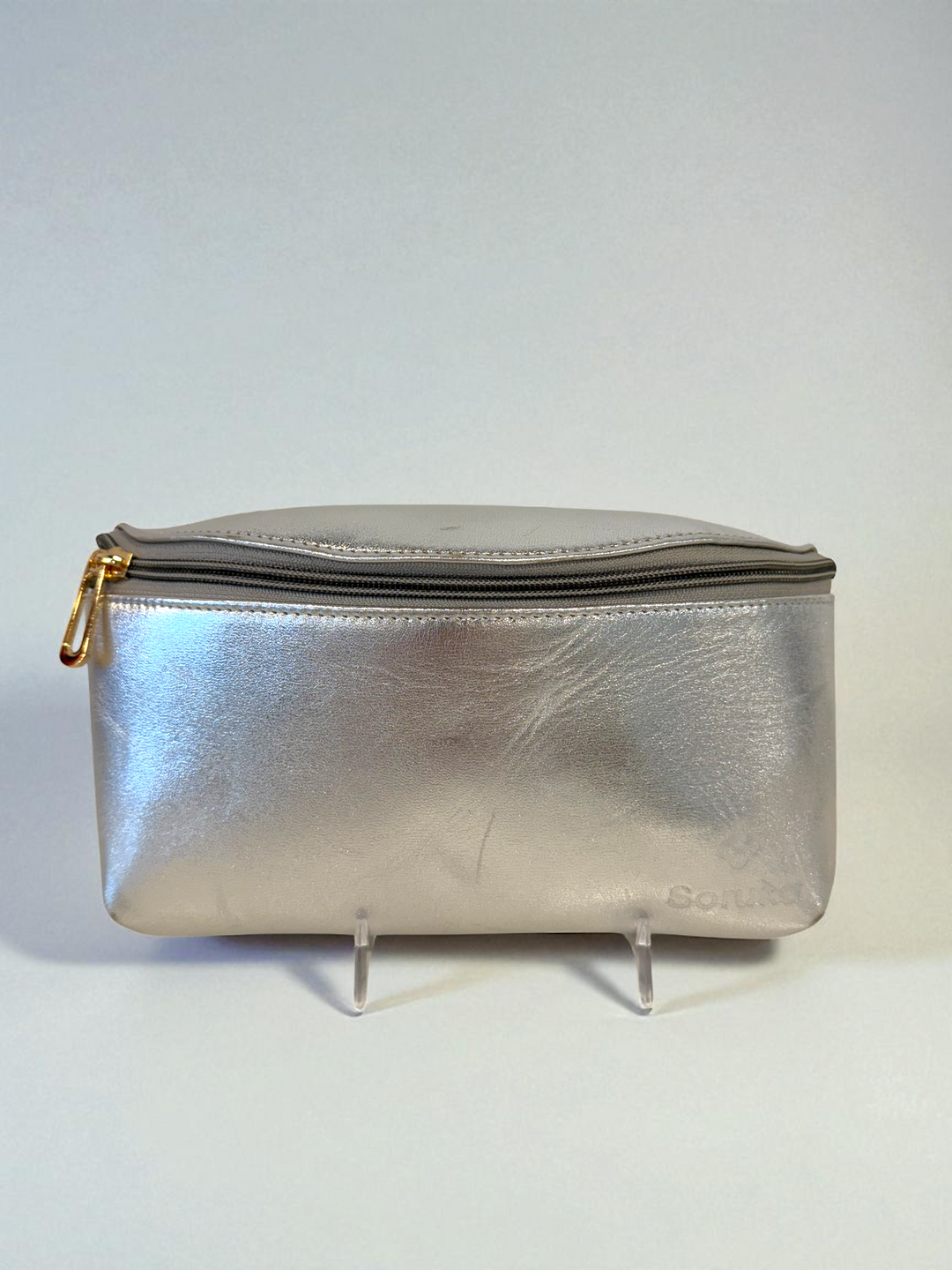 Silver metallic pouch with gold zipper on a white background
