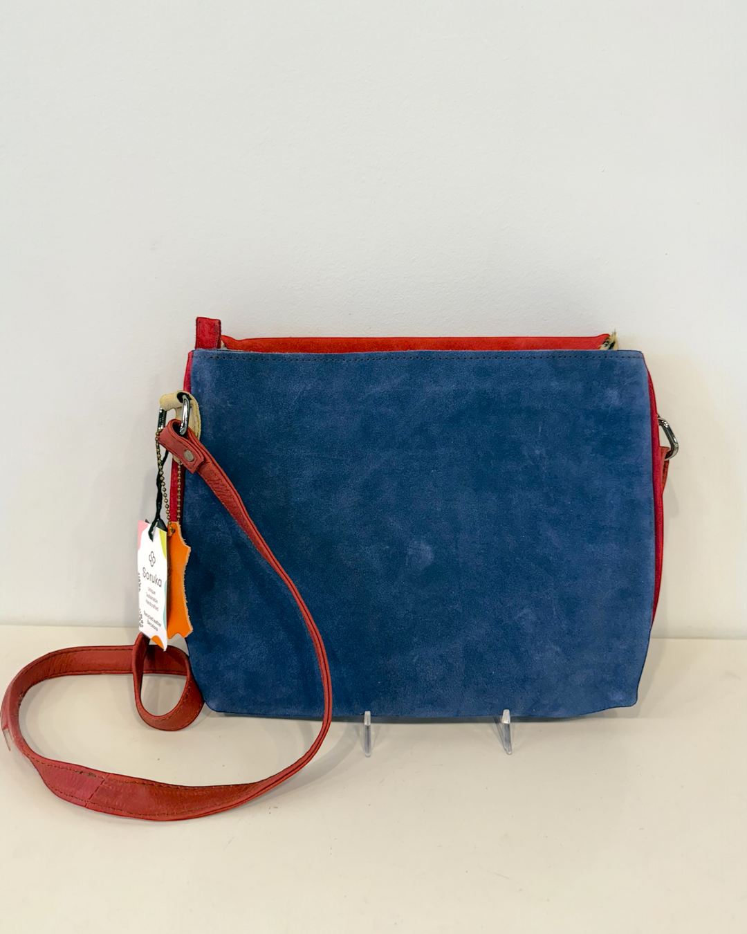 Blue handbag with red strap on a white background