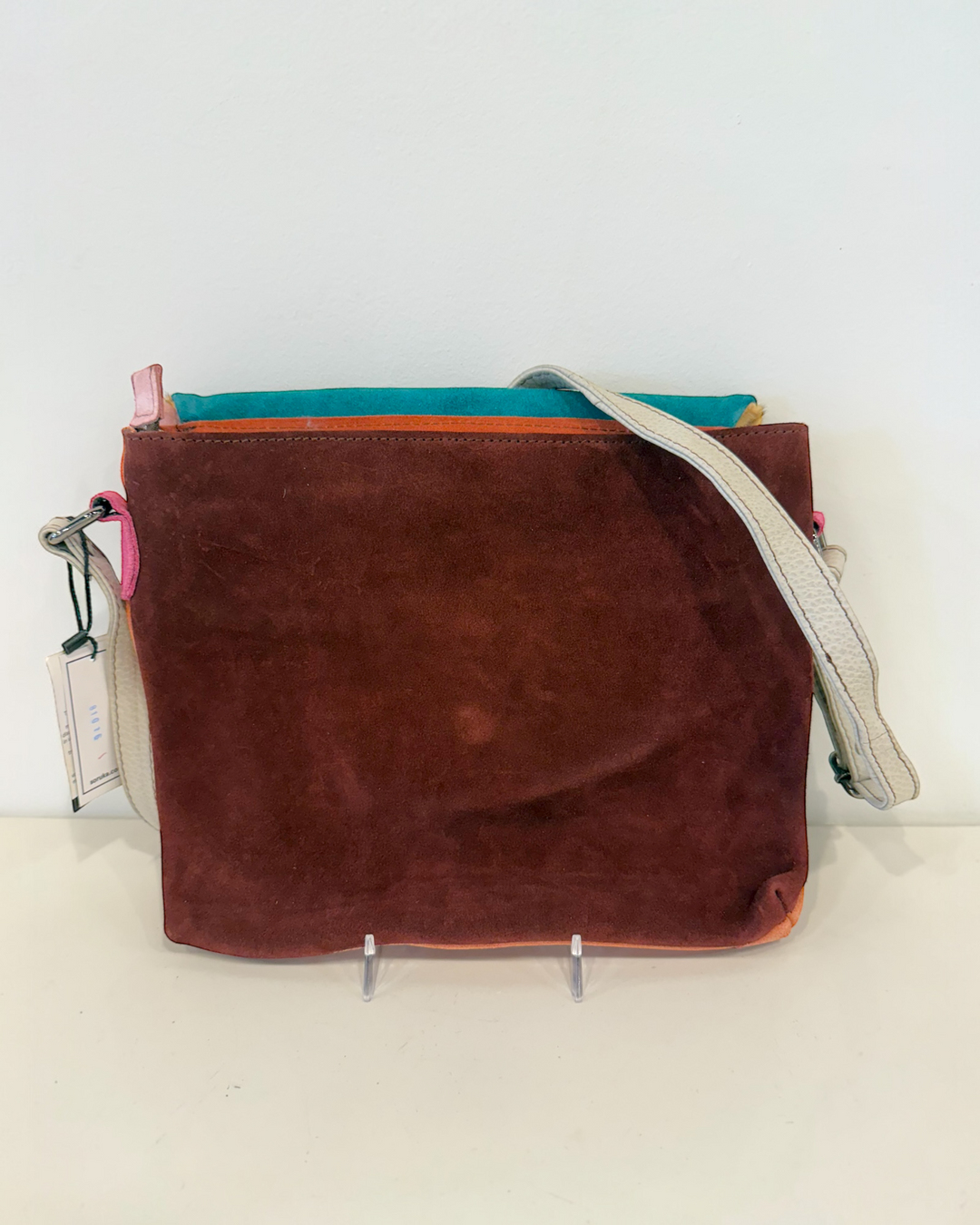 Brown suede handbag with a strap on a white background