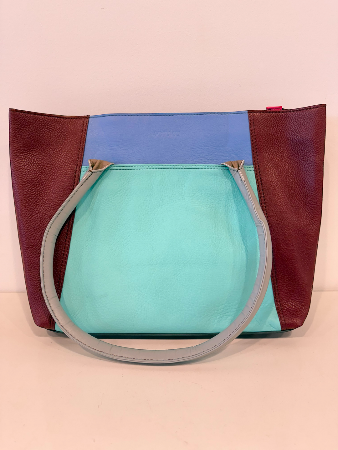 Multicolored handbag with a handle on a pink background