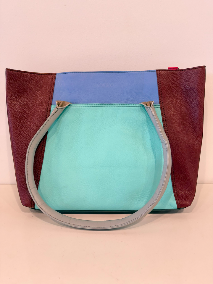 Multicolored handbag with a handle on a pink background