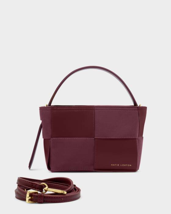 Burgundy handbag with matching strap on a light gray background