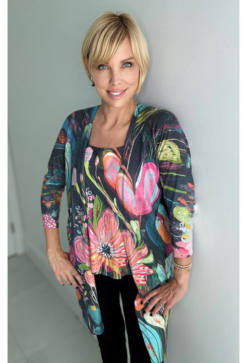 Woman wearing a colorful floral long cardigan against a plain background