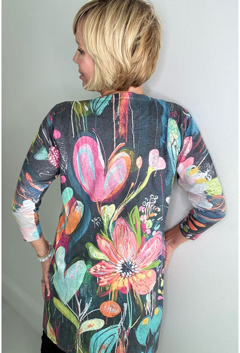 A lady wearing a colorful floral cardigan against a plain background