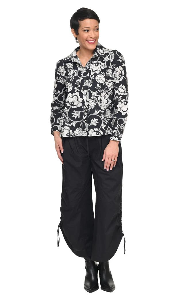 Woman wearing a black and white floral blouse with black pants on a white background