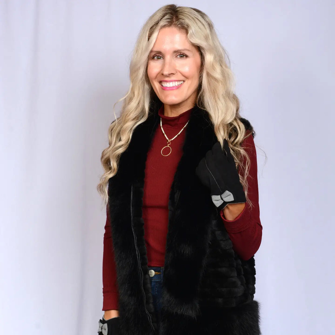 Woman wearing a red sweater and black fur vest against a white background